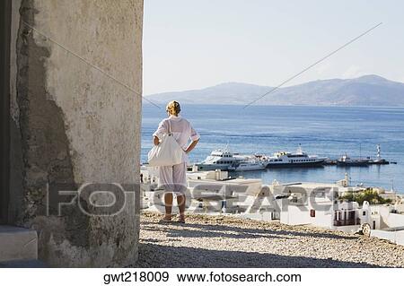 Stock Photo - Rear view of a woman looking at a view, Mykonos, Cyclades Islands, Greece. Fotosearch