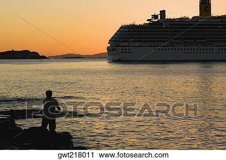 Stock Image - Silhouette of a cruise ship in the sea, Mykonos, Cyclades Islands, Greece. Fotosearch