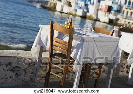 Table and chairs near a coast, Mykonos, Cyclades Islands, Greece View Large Photo Image Stock Photo - Table and chairs near a coast, Mykonos, Cyclades Islands, Greece. Fotosearch