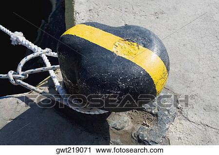Stock Image - Close-up of ropes tied around a bollard. Fotosearch
