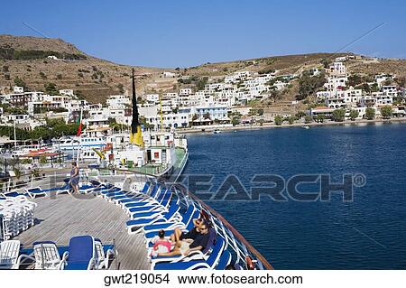 High angle view of tourists resting on lounge chairs on the deck of a ship, Skala, Patmos, Dodecanese Islands, Greece View Large Photo Image Picture - High angle view of tourists resting on lounge chairs on the deck of a ship, Skala, Patmos, Dodecanese Islands, Greece. Fotosearch