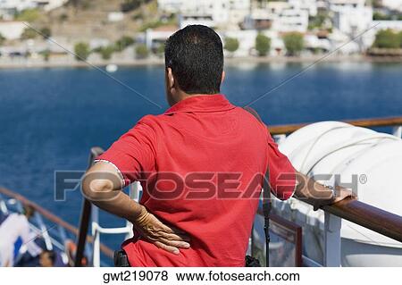 Rear view of a mid adult man standing on a yacht and looking at a view, Patmos, Dodecanese Islands, Greece View Large Photo Image Stock Photo - Rear view of a mid adult man standing on a yacht and looking at a view, Patmos, Dodecanese Islands, Greece. Fotosearch