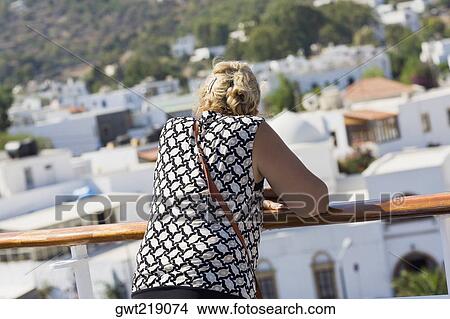 Rear view of a mid adult woman leaning against a railing and looking at a view, Patmos, Dodecanese Islands, Greece View Large Photo Image Picture - Rear view of a mid adult woman leaning against a railing and looking at a view, Patmos, Dodecanese Islands, Greece. Fotosearch