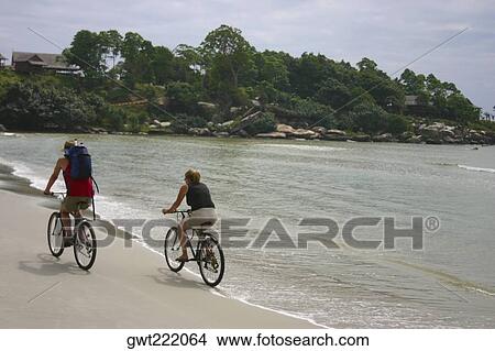 Rear view of a couple riding bicycles on the beach, Sihanoukville, Cambodia View Large Photo Image Picture - Rear view of a couple riding bicycles on the beach, Sihanoukville, Cambodia. Fotosearch
