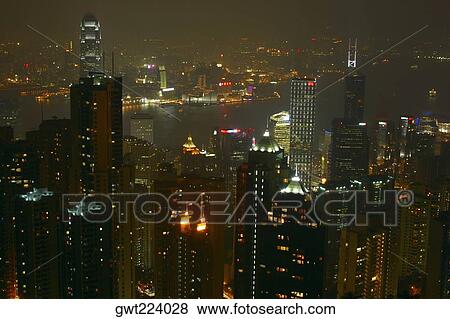 Stock Photo - High angle view of skyscrapers lit up at night in a city, Victoria Harbor, Hong Kong Island, Hong Kong, China. Fotosearch