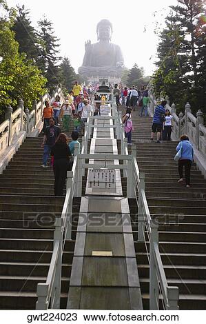 Stock Image - Low angle view of tourists visiting a monastery, Tian Tan Buddha, Po Lin Monastery, Ngong Ping, Lantau, Hong Kong, China. Fotosearch