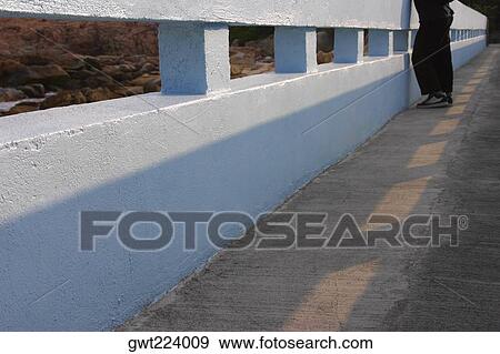 Stock Photo - Low section view of a person standing on a bridge, Lantau, Hong Kong, China. Fotosearch
