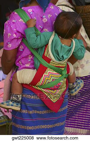 Stock Photo - Rear view of a woman carrying her baby on her back, Luang Prabang, Laos. Fotosearch