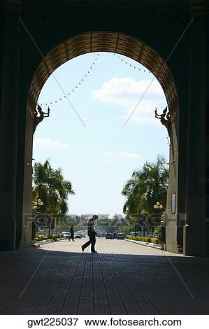 Stock Photo - Side profile of two people walking on the footpath in front of an arch, Victoria Memorial, Laos. Fotosearch