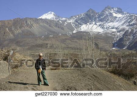 Stock Image - Young woman standing in front of mountains, Muktinath, Annapurna Range, Himalayas, Nepal. Fotosearch