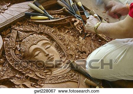 Stock Photo - Close-up of a person's hands carving a statue of Buddha on wood, Chiang Rai, Thailand. Fotosearch