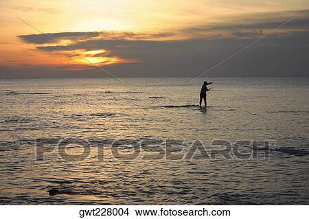 Picture - Silhouette of a fisherman fishing in the sea, Ko Lanta, Thailand. Fotosearch