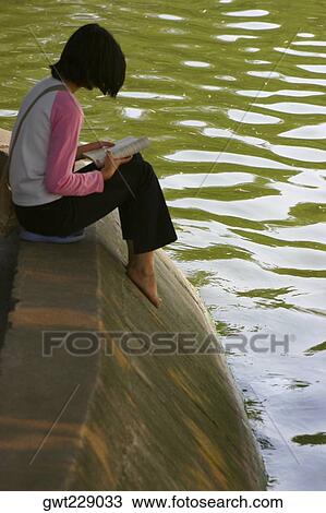 Side profile of a girl reading a book at the riverside, Hanoi, Vietnam View Large Photo Image Stock Image - Side profile of a girl reading a book at the riverside, Hanoi, Vietnam. Fotosearch