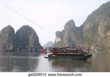 Tourboats in a bay rock formations in the background, Halong Bay, Vietnam View Large Photo Image Picture - Tourboats in a bay rock formations in the background, Halong Bay, Vietnam. Fotosearch