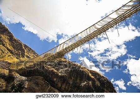 Stock Photo - Low angle view of a rope bridge across a mountain, Queswachaca, Peru. Fotosearch