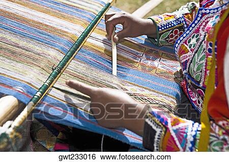 Stock Photograph - Mid section view of a woman weaving in a loom, Aguanacancha, Peru. Fotosearch
