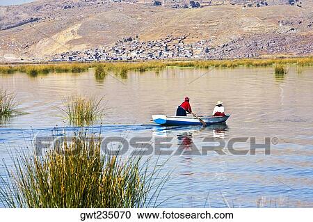 Stock Image - Two people rowing a boat in a lake, Lake Titicaca, Puno, Puno Region, Puno Province, Peru. Fotosearch