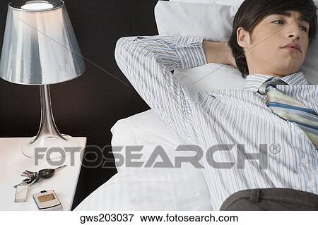 Businessman lying on the bed View Large Photo Image Stock Photo - Businessman lying on the bed. Fotosearch