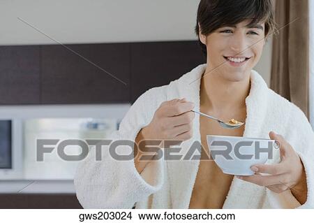 Picture - Close-up of a young man having food with a spoon. Fotosearch