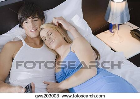 High angle view of a young couple lying on the bed and watching television View Large Photo Image Stock Photo - High angle view of a young couple lying on the bed and watching television. Fotosearch