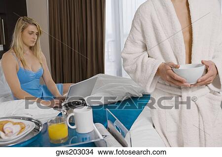 Mid section view of a young man holding a bowl with a young woman using a laptop View Large Photo Image Picture - Mid section view of a young man holding a bowl with a young woman using a laptop. Fotosearch