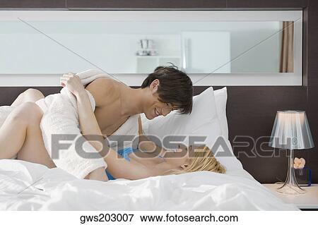Stock Photo - Side profile of a couple romancing on the bed. Fotosearch