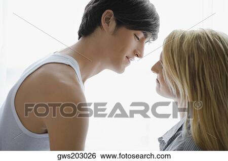 Side profile of a young couple romancing View Large Photo Image Stock Photograph - Side profile of a young couple romancing. Fotosearch
