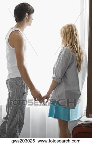 Side profile of a young couple standing near a window View Large Photo Image Stock Photography - Side profile of a young couple standing near a window. Fotosearch