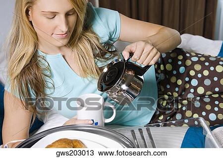 Young woman pouring tea into a tea cup View Large Photo Image Stock Image - Young woman pouring tea into a tea cup. Fotosearch