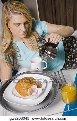 Stock Photography - Young woman pouring tea into a tea cup. Fotosearch