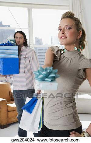 Portrait of a young couple holding gifts and shopping bags View Large Photo Image Picture - Portrait of a young couple holding gifts and shopping bags. Fotosearch