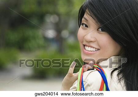 Portrait of a young woman carrying shopping bags and smiling View Large Photo Image Picture - Portrait of a young woman carrying shopping bags and smiling. Fotosearch