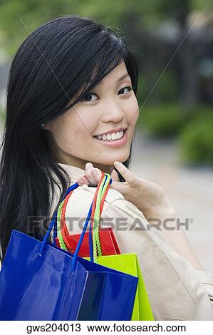 Portrait of a young woman carrying shopping bags and smiling View Large Photo Image Stock Image - Portrait of a young woman carrying shopping bags and smiling. Fotosearch