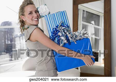 Portrait of a young woman holding gifts and smiling View Large Photo Image Stock Image - Portrait of a young woman holding gifts and smiling. Fotosearch