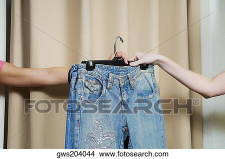 Sales clerk giving a jeans to a customer's hand View Large Photo Image Picture - Sales clerk giving a jeans to a customer's hand. Fotosearch