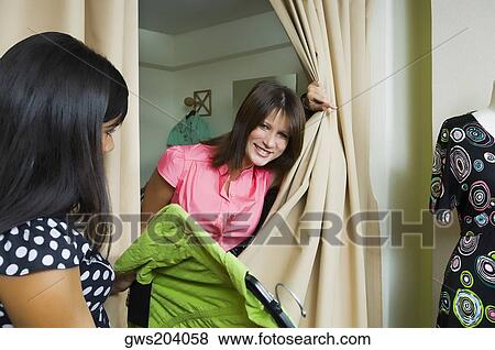 Side profile of a sales clerk giving a dress to a young woman View Large Photo Image Stock Photo - Side profile of a sales clerk giving a dress to a young woman. Fotosearch
