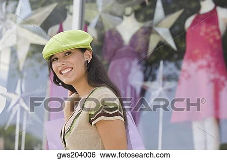 Side profile of a young woman carrying a shopping bag and smiling View Large Photo Image Stock Photograph - Side profile of a young woman carrying a shopping bag and smiling. Fotosearch