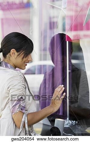 Side profile of a young woman window shopping View Large Photo Image Picture - Side profile of a young woman window shopping. Fotosearch