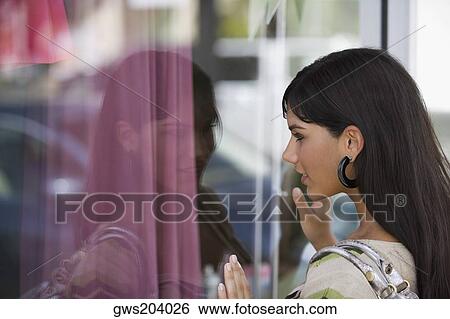Side profile of a young woman window shopping View Large Photo Image Stock Photograph - Side profile of a young woman window shopping. Fotosearch