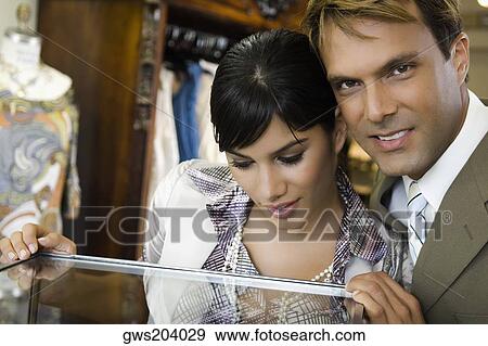 Young woman looking in a display cabinet with a mid adult man smiling beside her View Large Photo Image Stock Photo - Young woman looking in a display cabinet with a mid adult man smiling beside her. Fotosearch