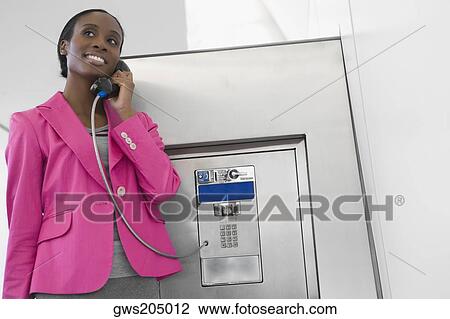 Businesswoman talking on a pay phone at an airport View Large Photo Image Stock Image - Businesswoman talking on a pay phone at an airport. Fotosearch