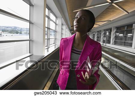 Stock Image - Close-up of a businesswoman holding a passport and looking away. Fotosearch
