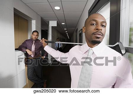 Stock Image - Portrait of a businessman holding a golf club. Fotosearch