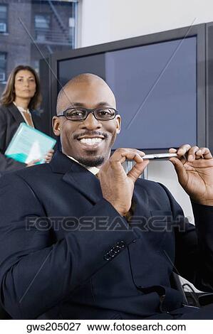 Portrait of a businessman smiling with a businesswoman standing in the background View Large Photo Image Stock Photo - Portrait of a businessman smiling with a businesswoman standing in the background. Fotosearch