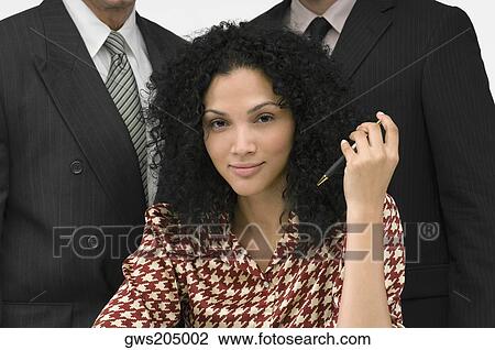 Portrait of a businesswoman holding a pen with two businessmen behind her View Large Photo Image Stock Image - Portrait of a businesswoman holding a pen with two businessmen behind her. Fotosearch