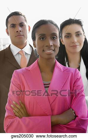 Portrait of a businesswoman smiling with two business executives standing behind her View Large Photo Image Stock Image - Portrait of a businesswoman smiling with two business executives standing behind her. Fotosearch