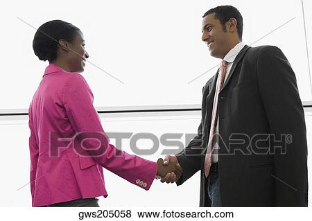 Side profile of a businessman and a businesswoman shaking hands at an airport View Large Photo Image Stock Photo - Side profile of a businessman and a businesswoman shaking hands at an airport. Fotosearch