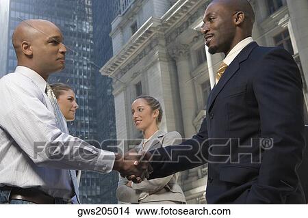 Side profile of two businessmen shaking hands with two businesswomen smiling View Large Photo Image Picture - Side profile of two businessmen shaking hands with two businesswomen smiling. Fotosearch