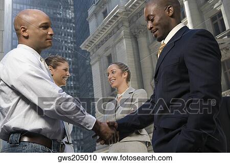 Side profile of two businessmen shaking hands with two businesswomen smiling View Large Photo Image Stock Image - Side profile of two businessmen shaking hands with two businesswomen smiling. Fotosearch