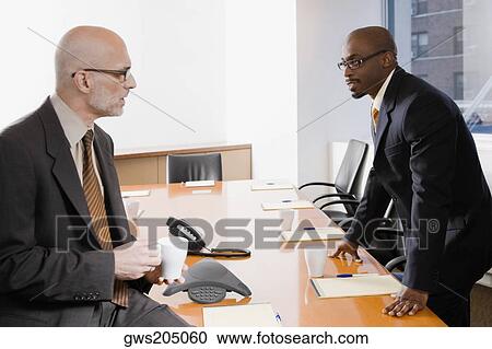 Stock Image - Two businessmen discussing in a conference room. Fotosearch